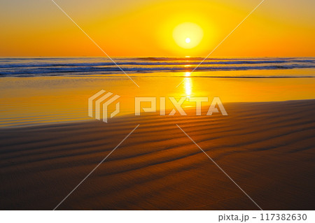 黄金色の空と水平線から昇る朝日を背景に輝くいわき市薄磯海岸の砂紋　Ver4 117382630