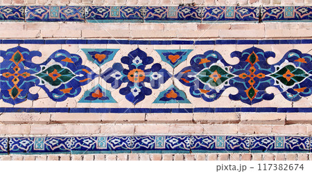 Horizontal background with detail of ancient mosaic walls with clay details and geometric ceramic tile ornament. Traditional iranian tile decorations Horizontal background with detail of ancient mosaic walls with clay details and geometric ceramic tile ornament. Traditional iranian tile decorations 117382674