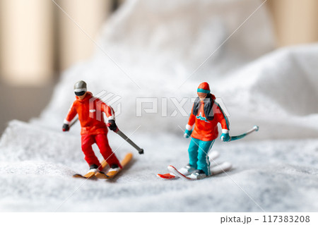 Miniature figurine of a skier in motion skiing across a white snowy landscape 117383208