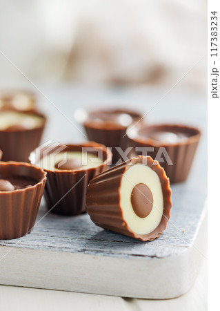 Sweet pralines. Chocolate truffles on cutting board on white table. 117383234