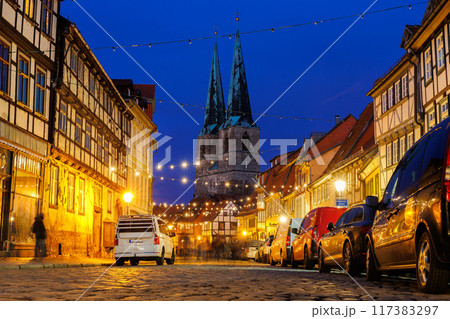 Charming Quedlinburg town evening street view illuminated with Christmas lights old St. Nicholas Church St. Nicholas Kirche background historical half-timbered houses facade. Festive city German 117383297