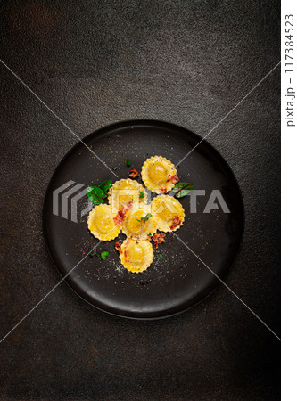 fresh ravioli, with butter, spices and herbs, fried bacon, on a black plate, top view, dark background, no people, fresh ravioli, with butter, spices and herbs, fried bacon, on a black plate, top view, dark background, no people, 117384523