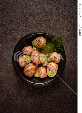snails stuffed in Burgundy, on a black plate, with grape leaves, French cuisine, no people, 117384524