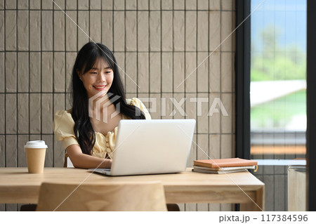 Attractive young asian woman working with laptop in modern co working space 117384596