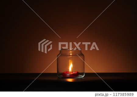 red candle in glass on orange Halloween background. Spooky minimalist banner 117385989
