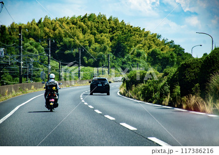 道路を走るバイクと車 117386216
