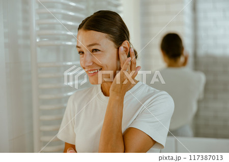 Engaging in a SelfCare Routine within a Bright and Inviting Bathroom Atmosphere 117387013