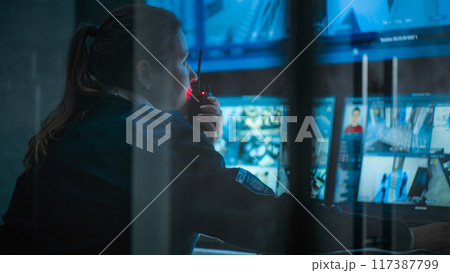 Female CCTV operator works on computer in monitoring center with security cameras Female CCTV operator works on computer in monitoring center with security cameras 117387799