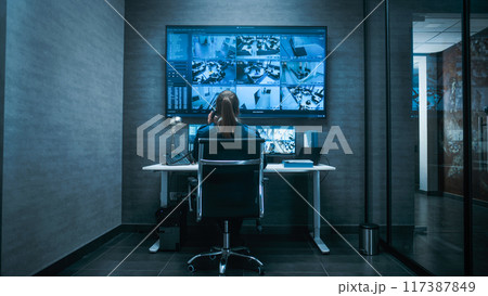 Female CCTV operator watches security cameras on multiple monitors and digital screen Female CCTV operator watches security cameras on multiple monitors and digital screen 117387849