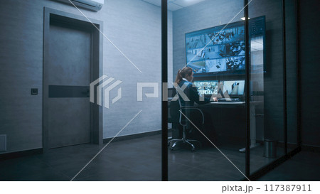 Female surveillance operator controls security cameras in monitoring center 117387911