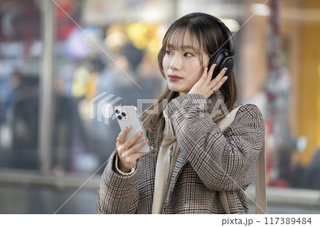 ヘッドホンをしてスマートフォンを持った若い女性　 117389484