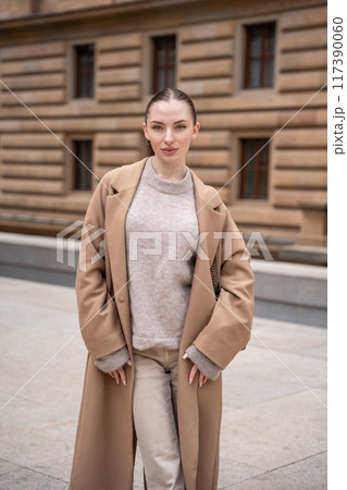Young beautiful woman wearing coat walking in the city centre of Prague, Europe 117390060