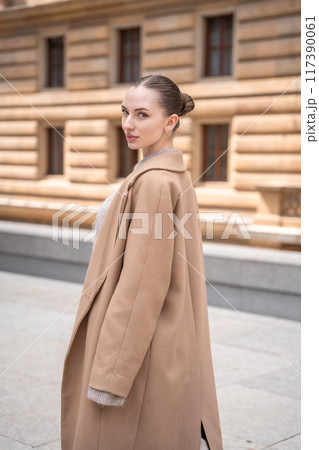 Young beautiful woman wearing coat walking in the city centre of Prague, Europe 117390061