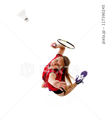High angle view of young woman, badminton player serving shuttlecock, throwing it up against white studio background. 117390245
