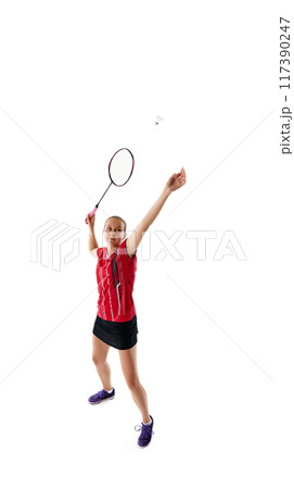 Dynamic photo of young woman, badminton player serving shuttlecock, throwing it up against white studio background. 117390247