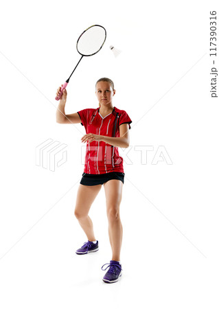 Competitive young woman standing ready to hitting shuttlecock in motion, repel enemy attack against white studio background. 117390316