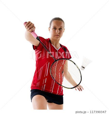 Dynamic portrait of young woman, badminton athlete with focused expression hitting shuttlecock against white studio background. Dynamic portrait of young woman, badminton athlete with focused expression hitting shuttlecock against white studio background. 117390347