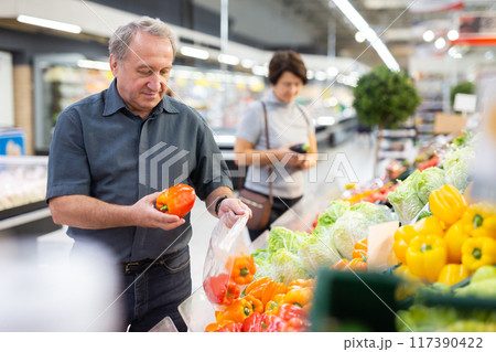 Elderly man chooses pepper in vegetable and fruit department 117390422
