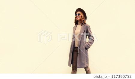 beautiful smiling young woman model in brown hat, coat on beige background, blank copy space beautiful smiling young woman model in brown hat, coat on beige background, blank copy space 117390752
