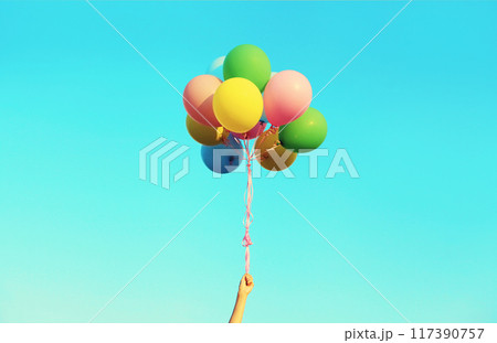 Hand holding bunch of multicolor balloons flying on blue sky background Hand holding bunch of multicolor balloons flying on blue sky background 117390757