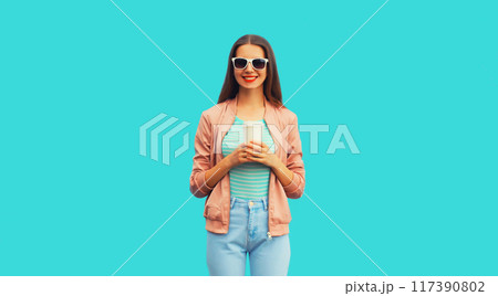 Portrait of happy smiling young woman with cup of coffee on blue background 117390802