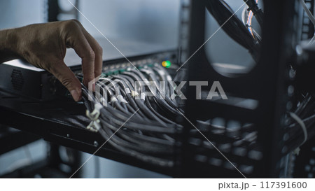 Close up of system administrator connecting cables with server rack 117391600