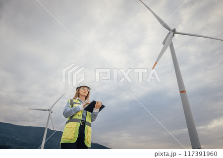 A female engineer inspects a wind turbine at a renewable energy facility, highlighting her key role in advancing sustainable practices and technological innovation in the industry 117391960
