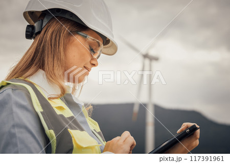 In the field of wind energy, professionals utilize advanced technology to monitor turbine performance conveniently using a tablet, ensuring efficiency and reliability in renewable energy production 117391961