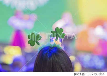 Young woman with green clover headband enjoys lively dance event, St. Patrick's Day celebrations 117391984