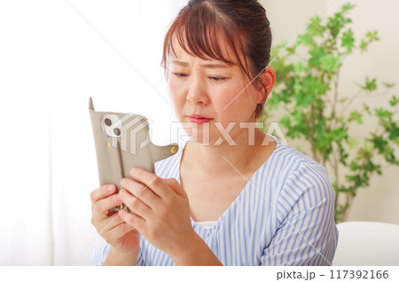 老眼でスマホが見えにくいミドル女性 老眼でスマホが見えにくいミドル女性 117392166
