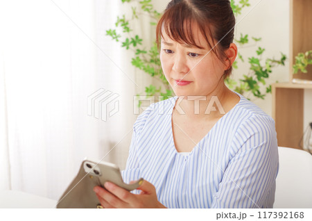 老眼でスマホが見えにくいミドル女性 老眼でスマホが見えにくいミドル女性 117392168