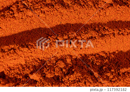 Abstract terracotta striped background of scattered paprika seasoning 117392182