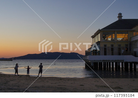 夕焼けに染まる海辺と親子のシルエット 117393184