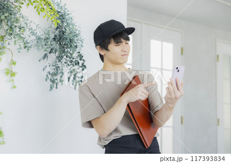 スマホを見るカフェの店員の若い男性　 117393834