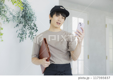 スマホを見るカフェの店員の若い男性 スマホを見るカフェの店員の若い男性 117393837