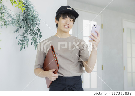 スマホを見るカフェの店員の若い男性　 117393838