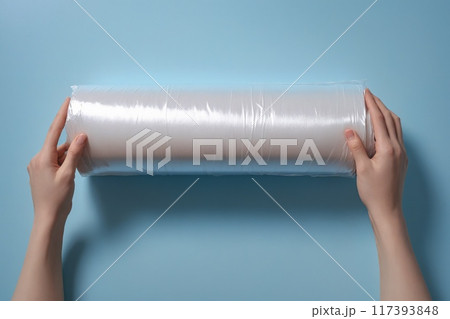 Woman's hand using a roll of transparent polyethylene food film for packing products on the pastel blue table. Empty place for text or logo. Illustration, painting 117393848