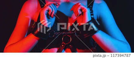 Submissive woman bottom slave girl with sexy breast with hands in leather handcuffs. BDSM sex with submission and domination 117394787