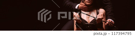 couple has BDSM sex with submission and domination. Dominant man with a whip flogger holds a sexy submissive woman bottom girl with handcuffed hands couple has BDSM sex with submission and domination. Dominant man with a whip flogger holds a sexy submissive woman bottom girl with handcuffed hands 117394795
