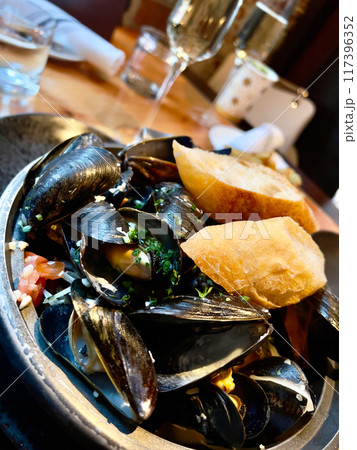Mussels with lemon and parsley on the wooden plate in restaurant 117396352