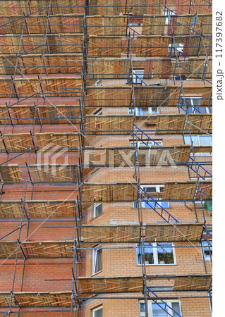A brick house under construction with wooden scaffolding 117397682