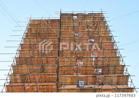 A brick house under construction with wooden scaffolding 117397683