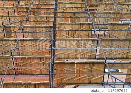 A brick house under construction with wooden scaffolding 117397685