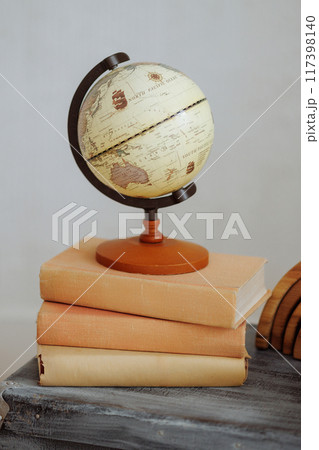 A globe sits on top of a stack of books 117398140