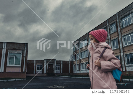 Little girl in pink coat with backpack in disadvantaged area goes to school Little girl in pink coat with backpack in disadvantaged area goes to school 117398142