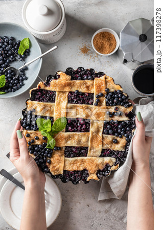 Woman hands holding homemade blueberry pie on light kitchen table background top view, flatly Woman hands holding homemade blueberry pie on light kitchen table background top view, flatly 117398278