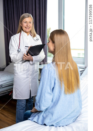Mature long-haired doctor talking to a pregnant woman and both looking involved 117399586