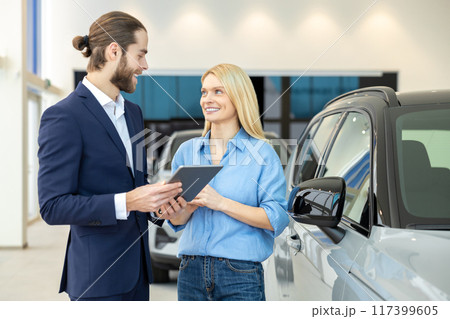 Woman negotiating car purchase with the dealer at automobile store 117399605
