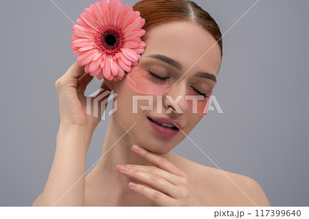 Young female with floral touch using skincare patches on face Young female with floral touch using skincare patches on face 117399640