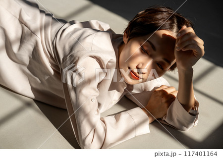 日差しが差し込むフローリングでくつろぐミドル女性 117401164